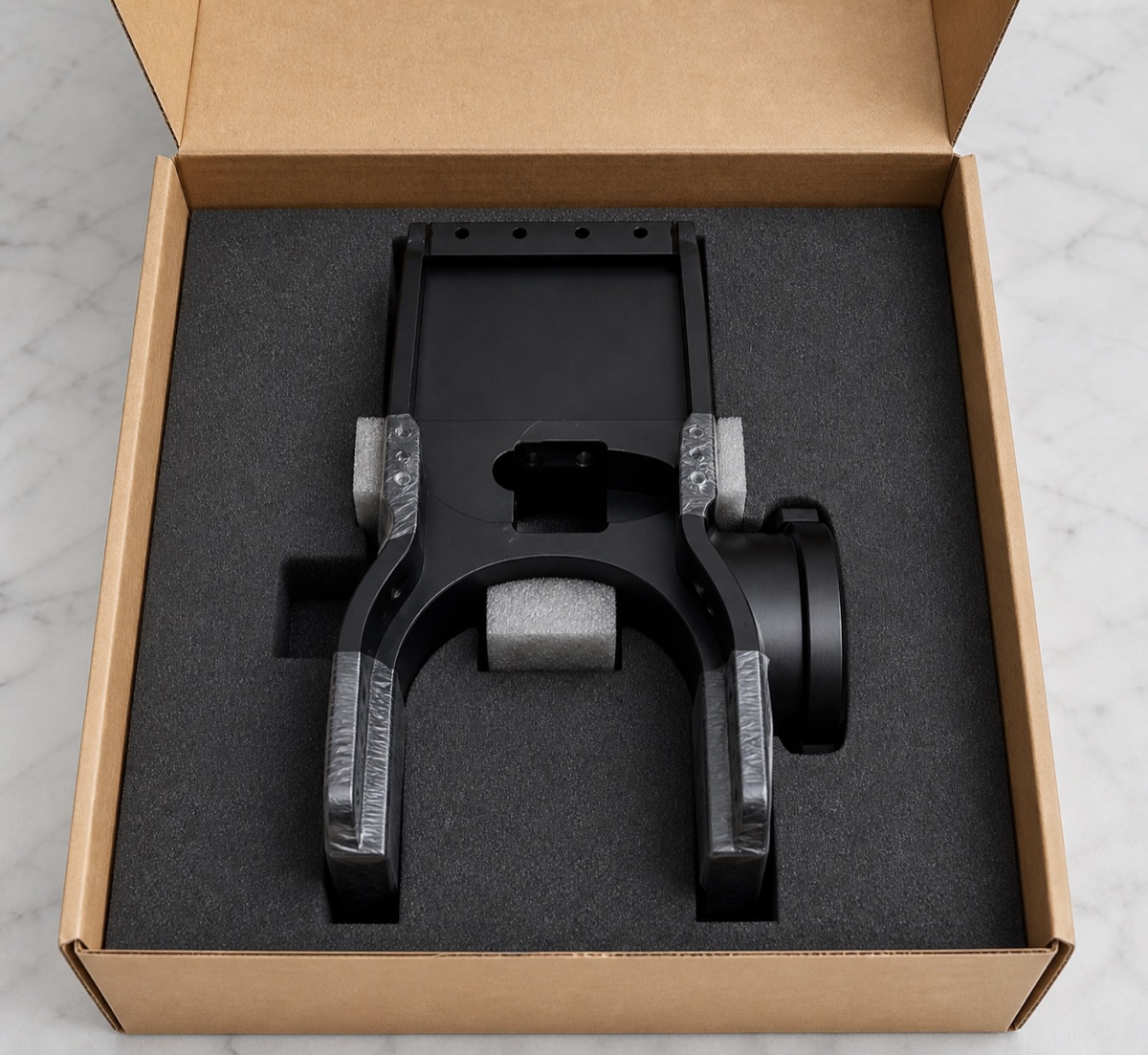 Foam packaging supporting the U-shaped opening of a black anodized robot module seat